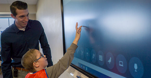 Elementary student in autism support program interacts with smart board in special education school
