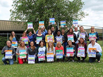 Special Education teachers, occupational therapists, speech therapists, and counselors smile together at their special education school.