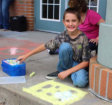 A young special education student smiles while working on an outdoor lesson