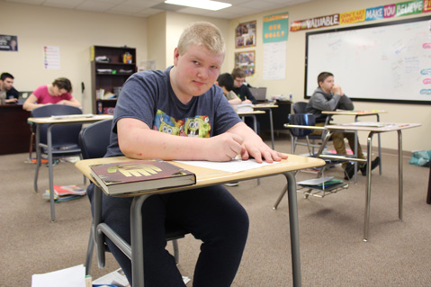 A special education high school student looks up from his desk while working on his lesson