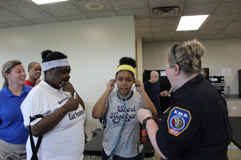 Special needs students smile as they work with EMTs and try on stethoscopes