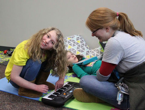 A special education teacher and two students play with a keyboard during their lesson