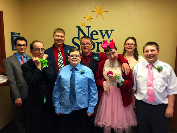 A group of high school studnets in formalware smile before prom at their special education school.