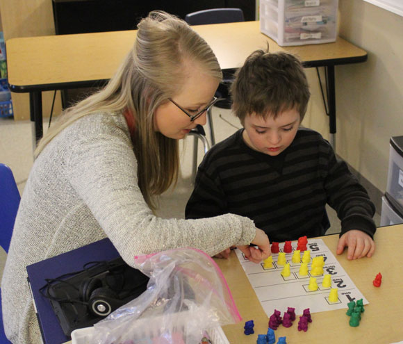 A special education teacher works with her elementary school student on a project.