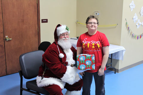 A special education student stands next to Santa Claus and smiles.