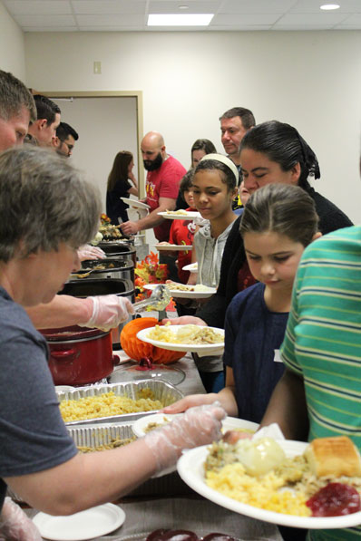Parents, students, and faculty wait in line for a holiday buffet at their special education school.