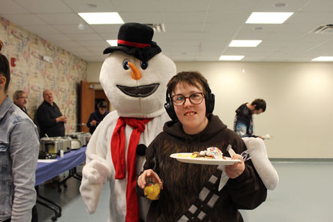 A man in a snowman costume stands behind a student at his special needs school.