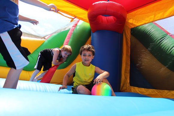Two elementary school students smile in a bounce house at their special education school.