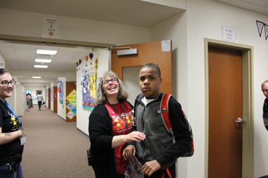 A boy and his special education teacher smile from the hallway.