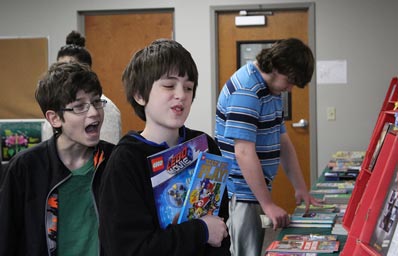 Two boys in an autism support educational program review books at a table in their school