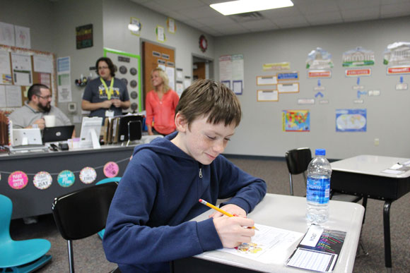 An elementary school special education student works on an assignment at his desk