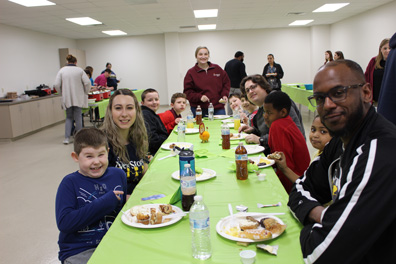 Special education students, staff, and families smile at a buffet.