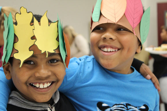 Two elementary school boys smile while wearing fall themed hats in their special education school.