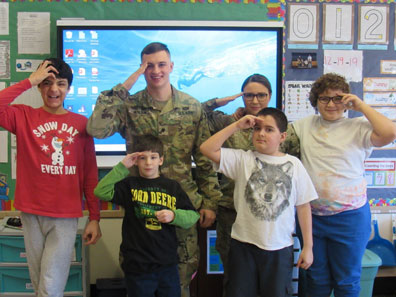 Four boys from a special education class and their teacher salute with a member of the armed forces who visited.