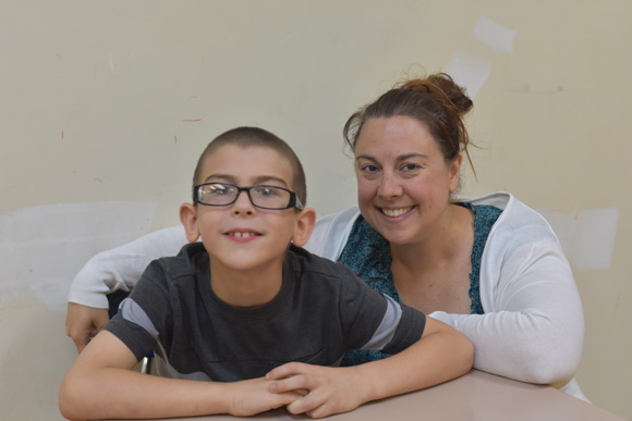 An elementary student smiles with his special education teacher.