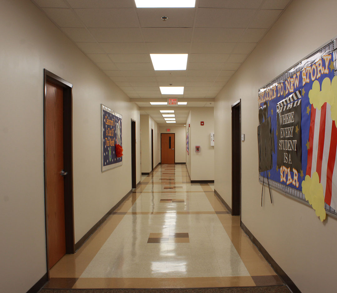 Hallway with colorful posters, tile flooring in white, beige and brown patterns.